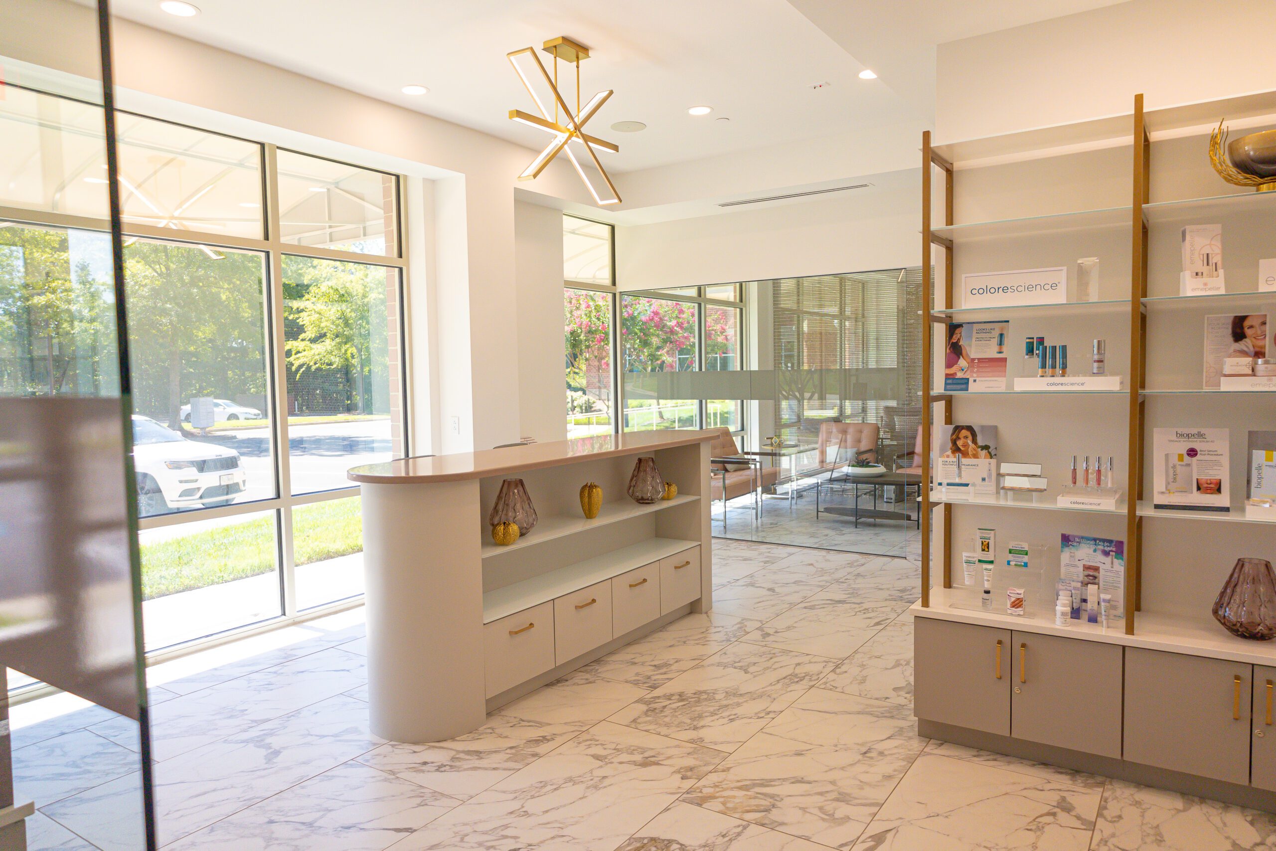 Bright lobby space with marble floors, gold light fixtures, product display shelves, and seating area near large windows.